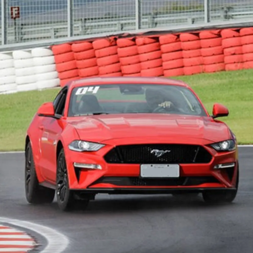 Carro esportivo em curva de autódromo com zebra vermelha e branca